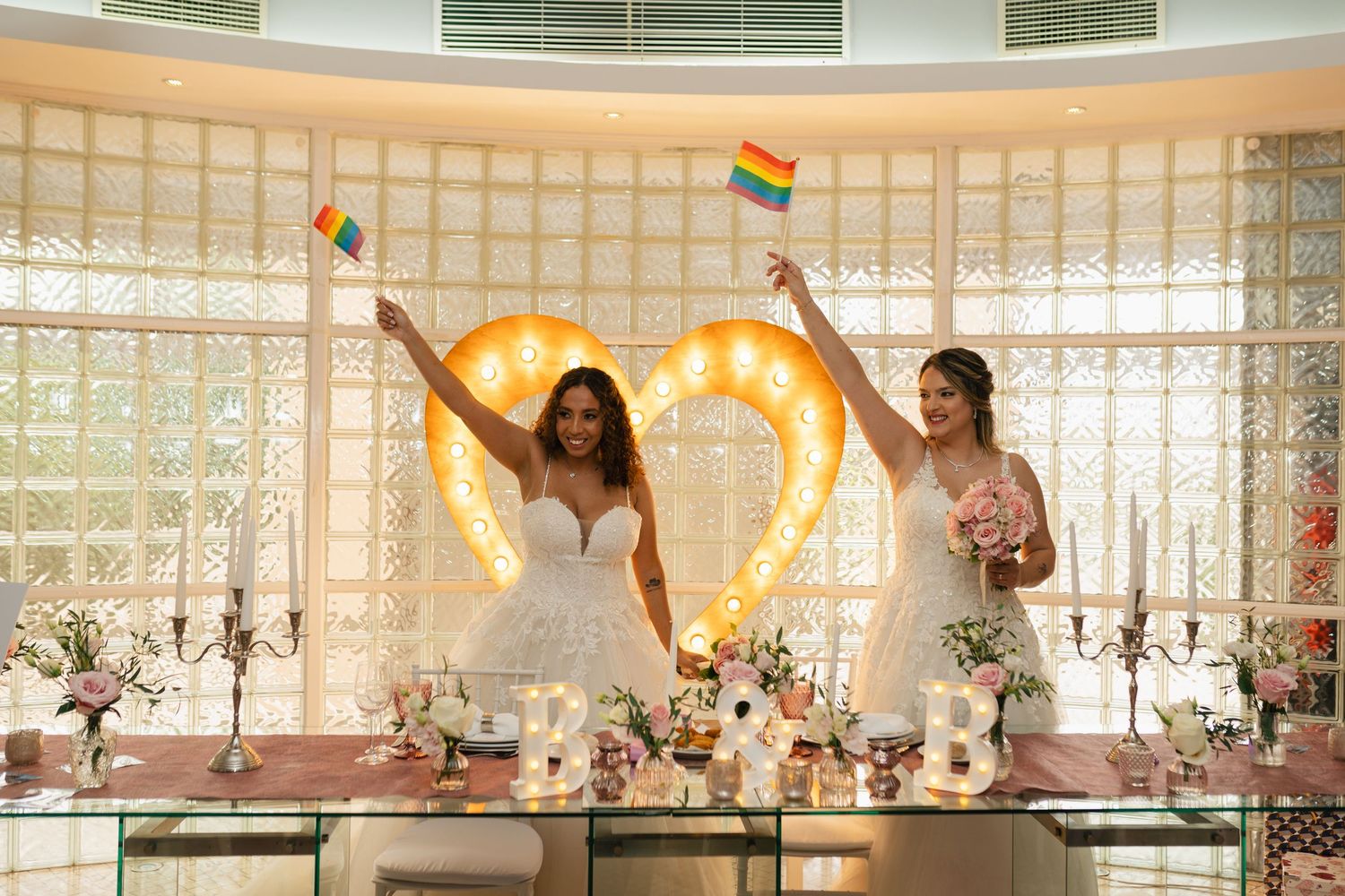 Wedding celebration with rainbow flags and joyful dancing in an elegant venue.