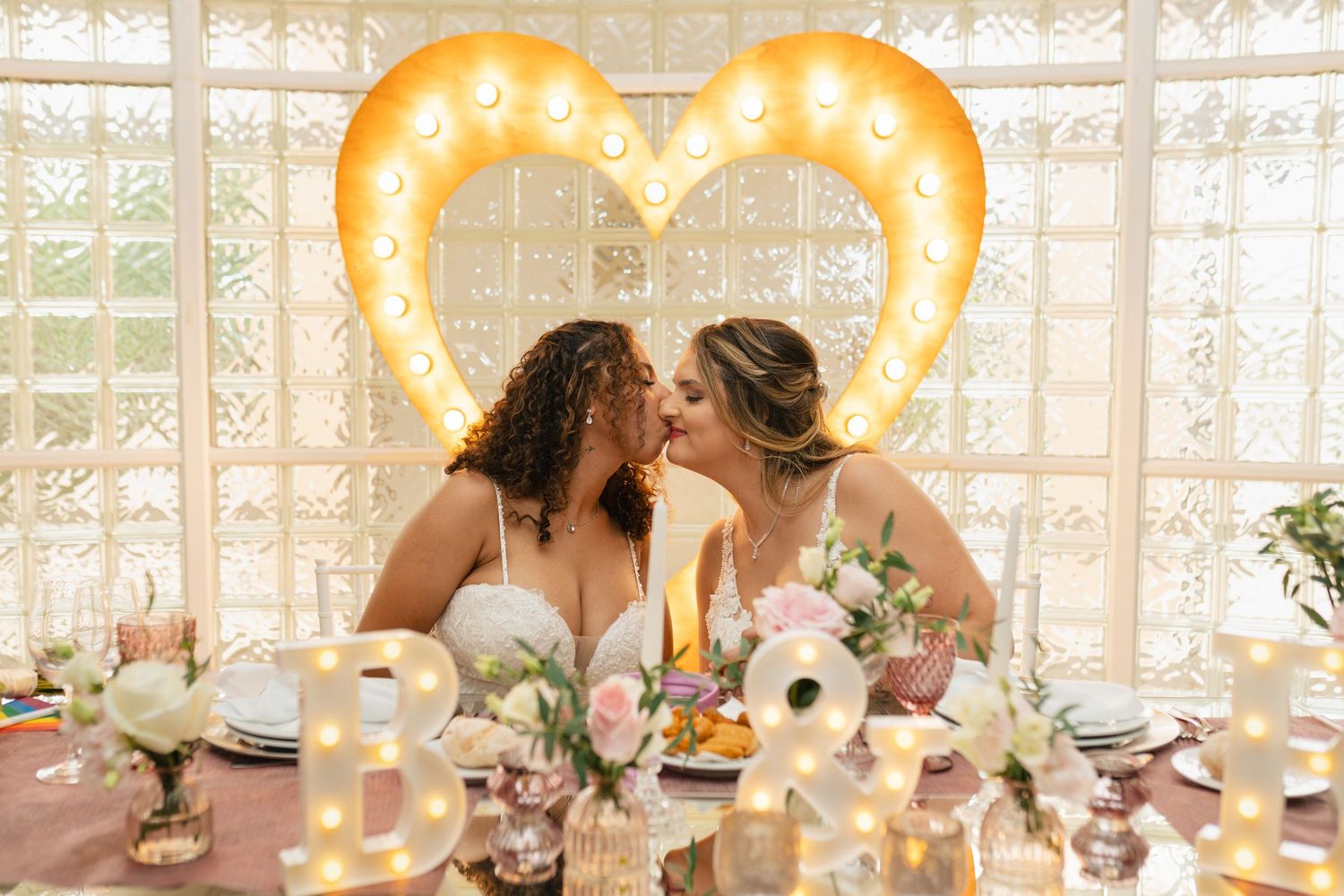 Wedding reception setup with illuminated heart decorations and elegant table settings.