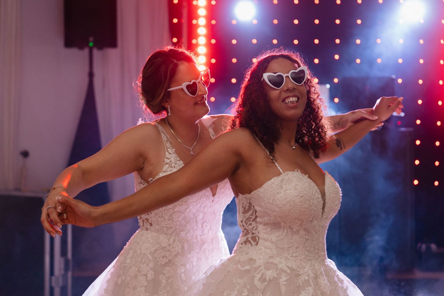 Wedding party dancing under colorful disco lights and atmospheric fog.