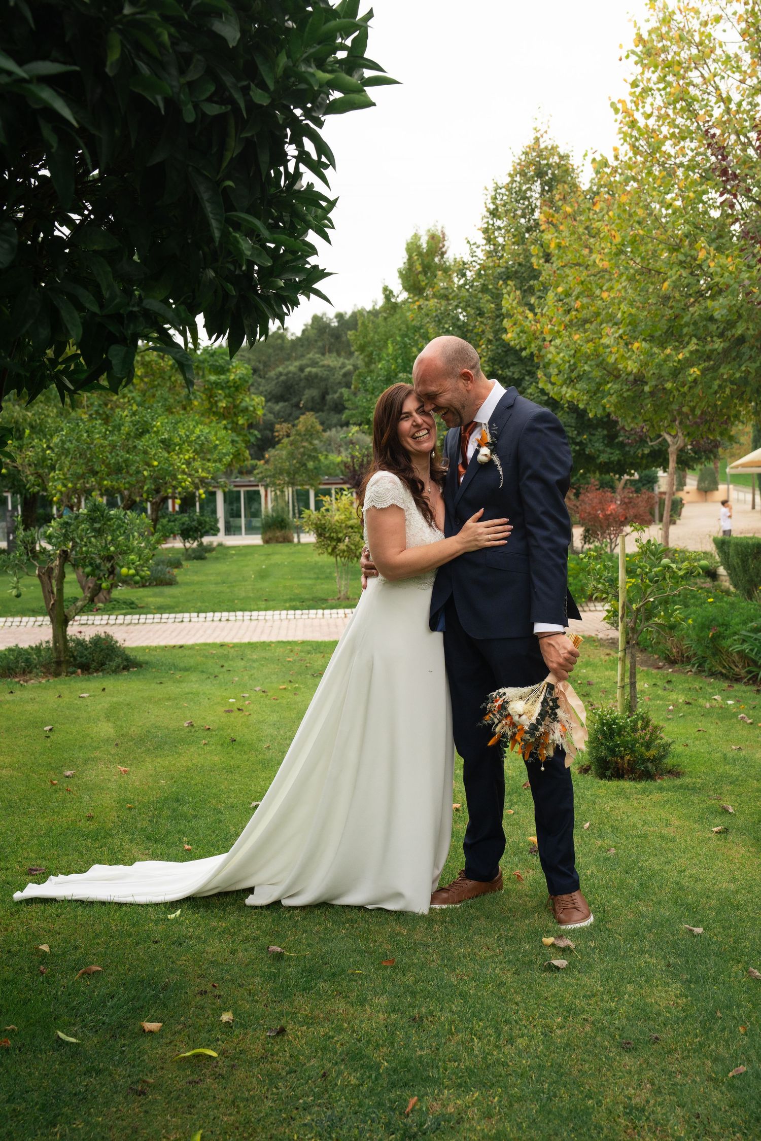 A couple shares a romantic dip pose on their wedding day surrounded by greenery.