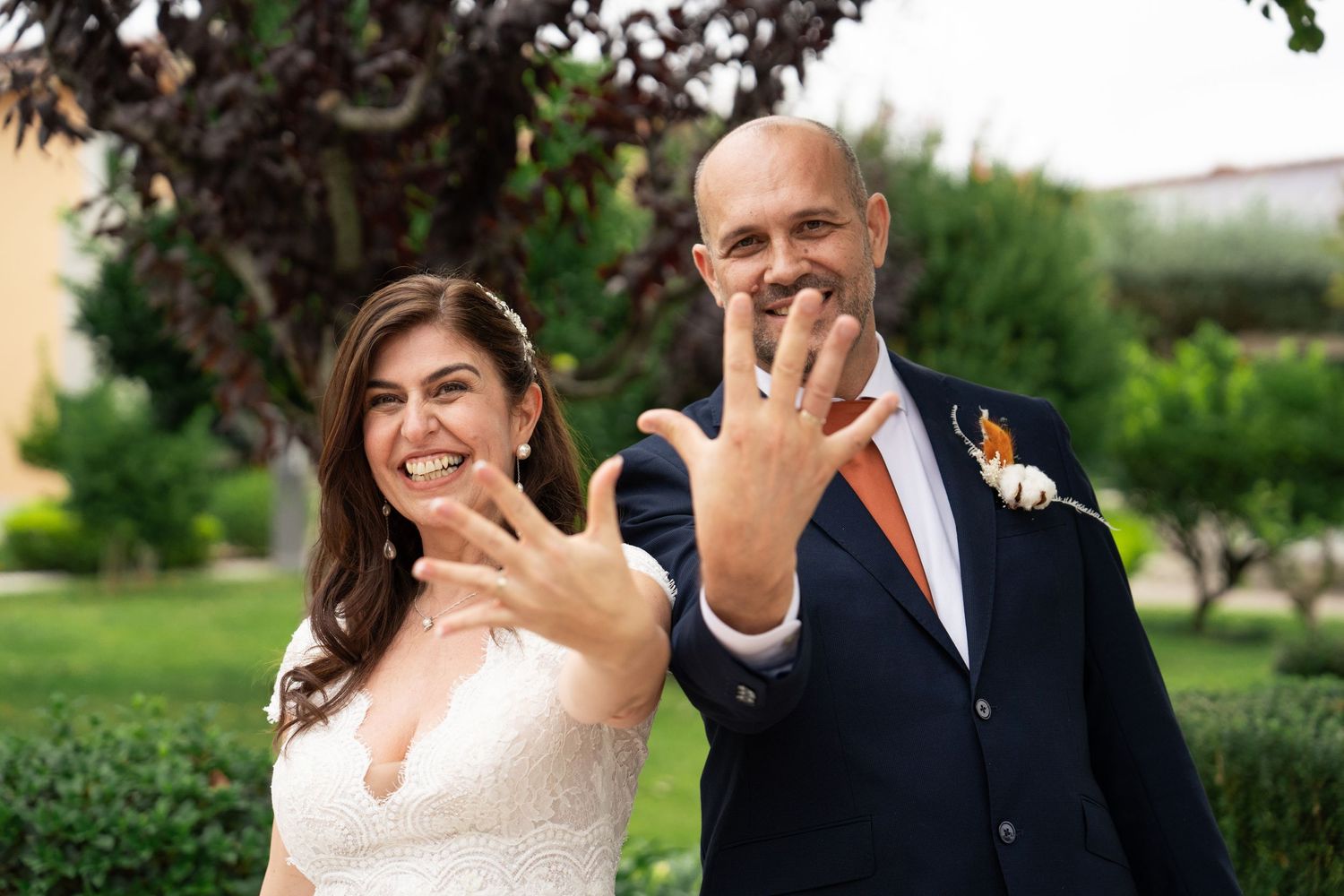 A couple poses playfully in a lush garden setting during their wedding photoshoot.