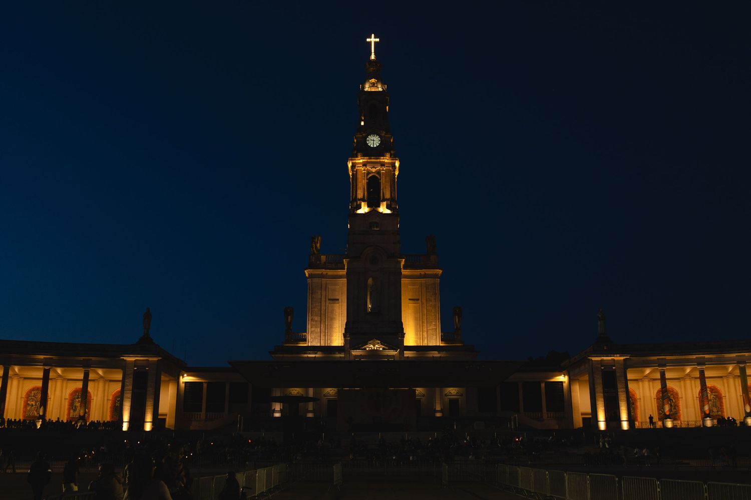 Illuminated church facade and tower against dark blue night sky.