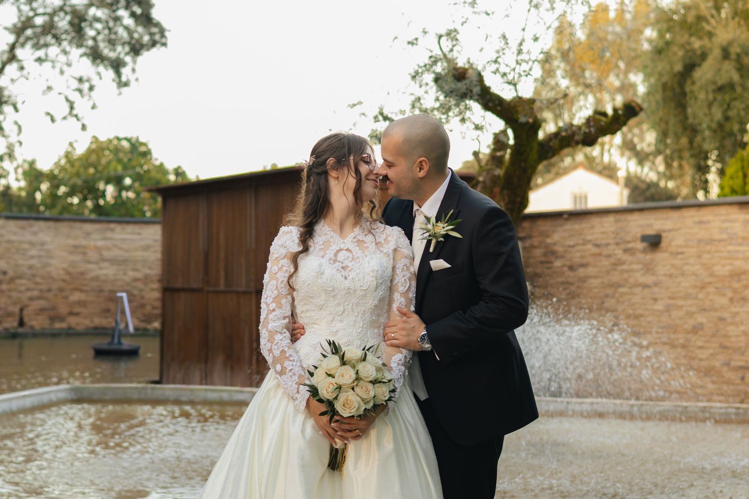 Elegant wedding portraits captured in natural outdoor setting with stone wall backdrop.