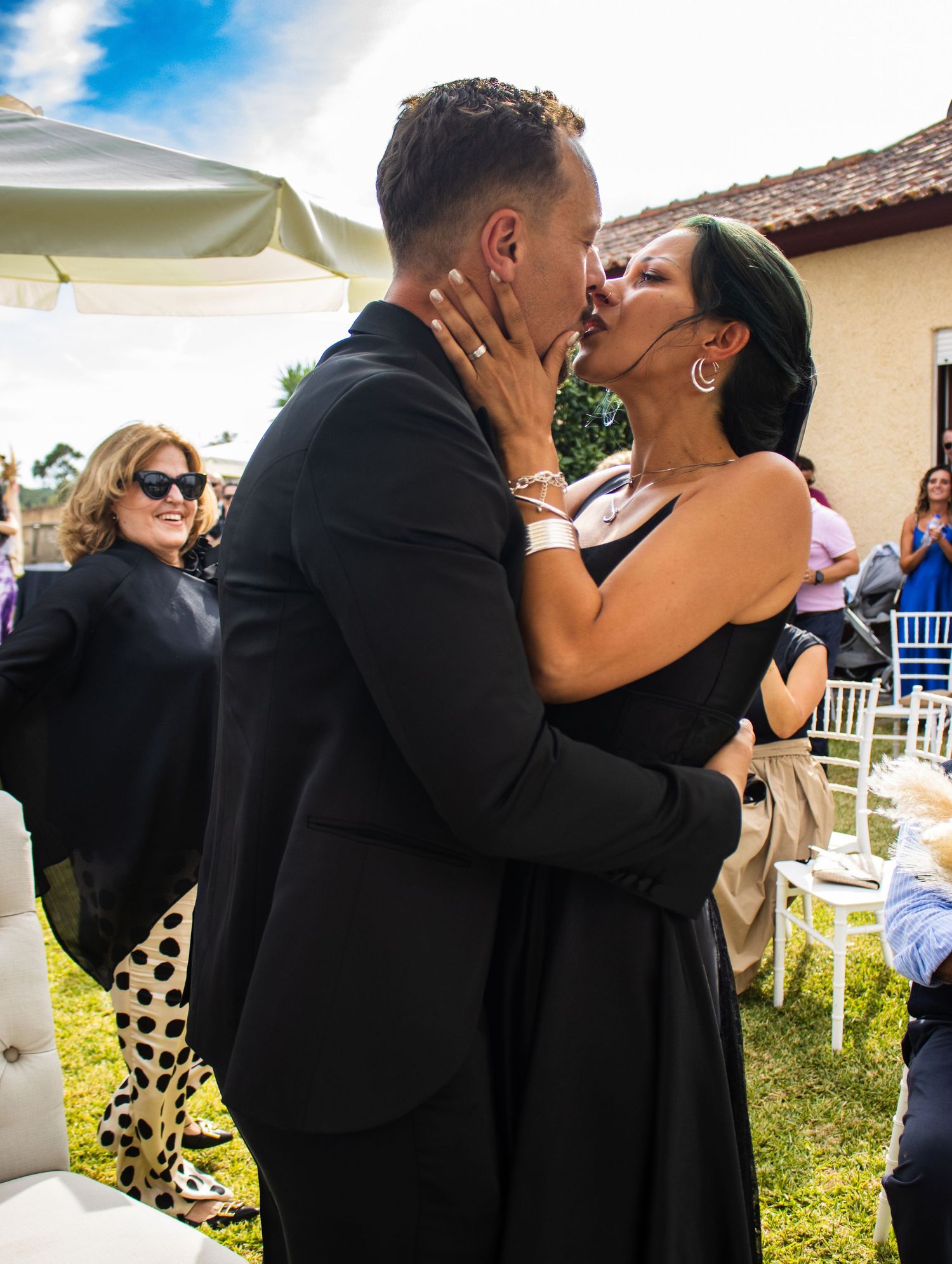 Newlywed couple sharing passionate kiss during outdoor wedding ceremony.