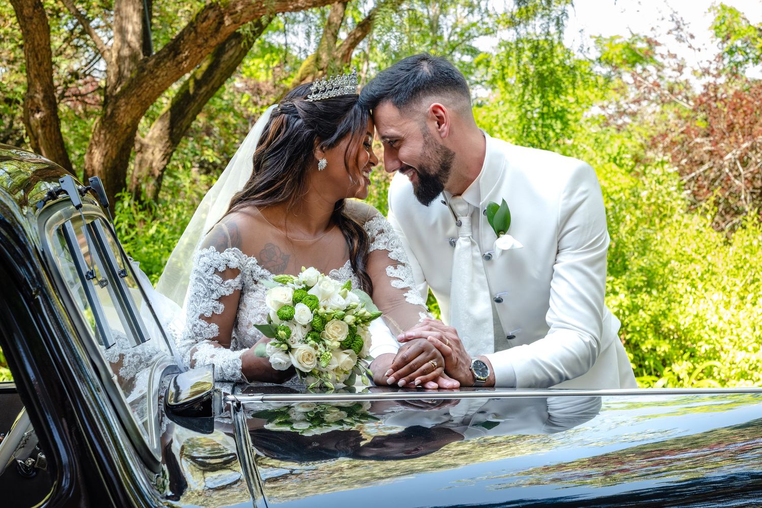 Wedding couple poses in romantic outdoor setting with vintage car.
