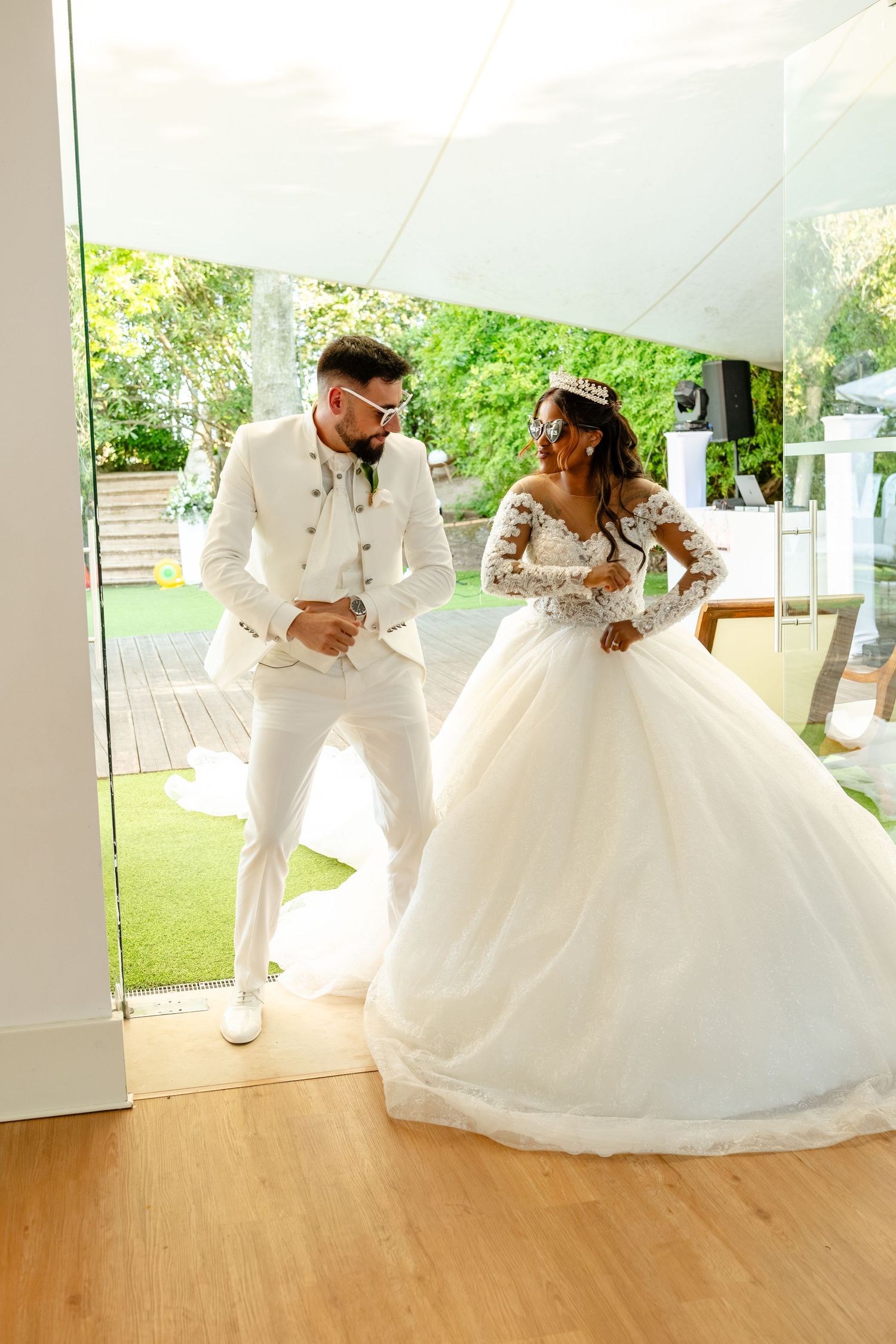 Wedding couple dancing together under white tent on wooden floor.