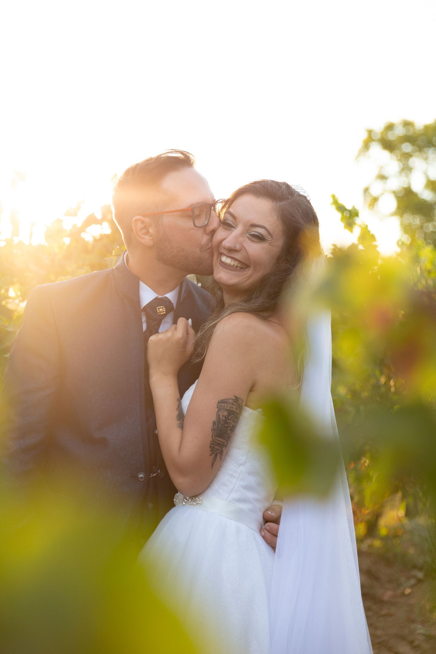 Sunlit wedding portraits show intimate moments between newlyweds in a vineyard setting.