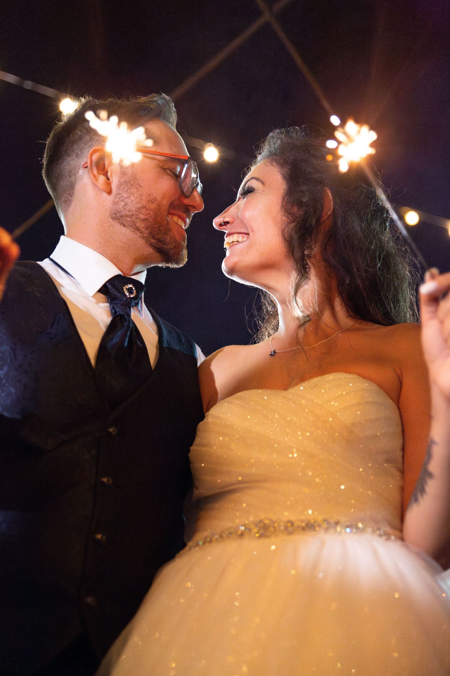 Wedding couple shares romantic moments under twinkling lights during their evening celebration.
