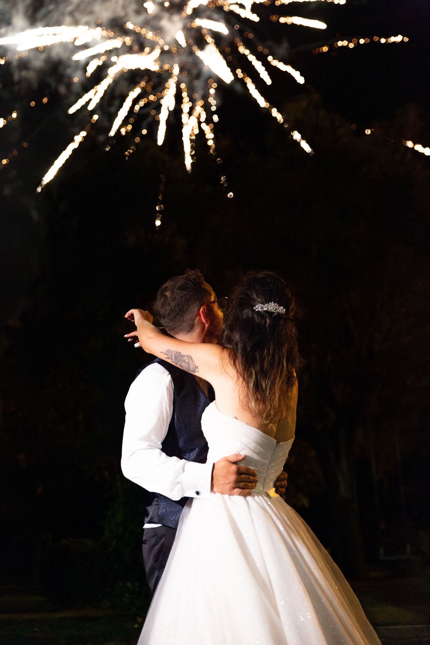 Wedding couple embraces under spectacular fireworks display during their celebration.