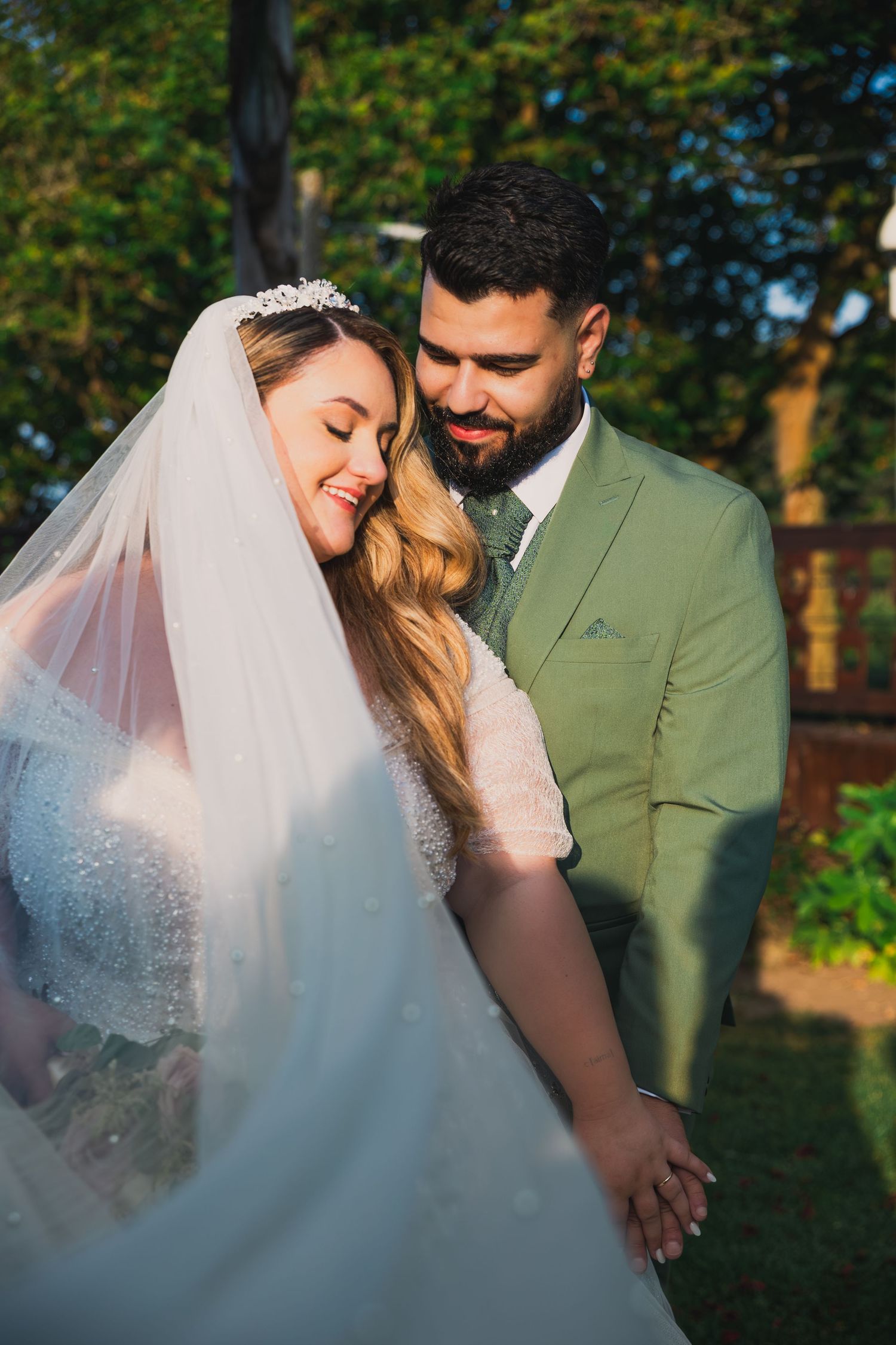 Romantic outdoor wedding portraits with a couple embracing in a garden setting.