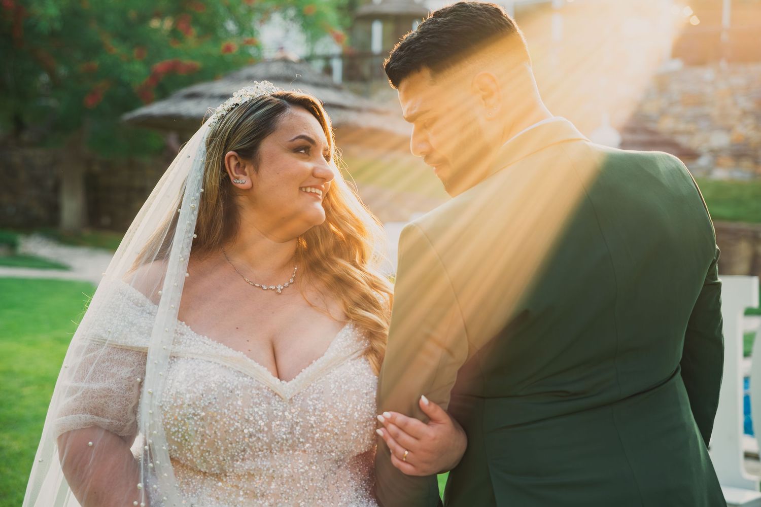 Golden hour wedding portrait with sunlight streaming through trees.