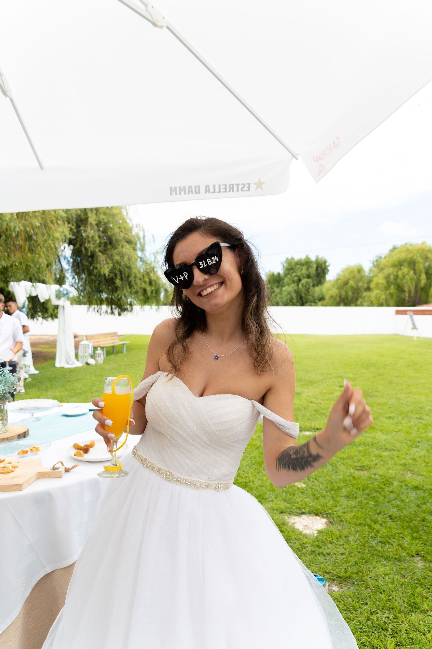 Joyful bride twirls in her white wedding dress on a sunny lawn during reception celebrations.