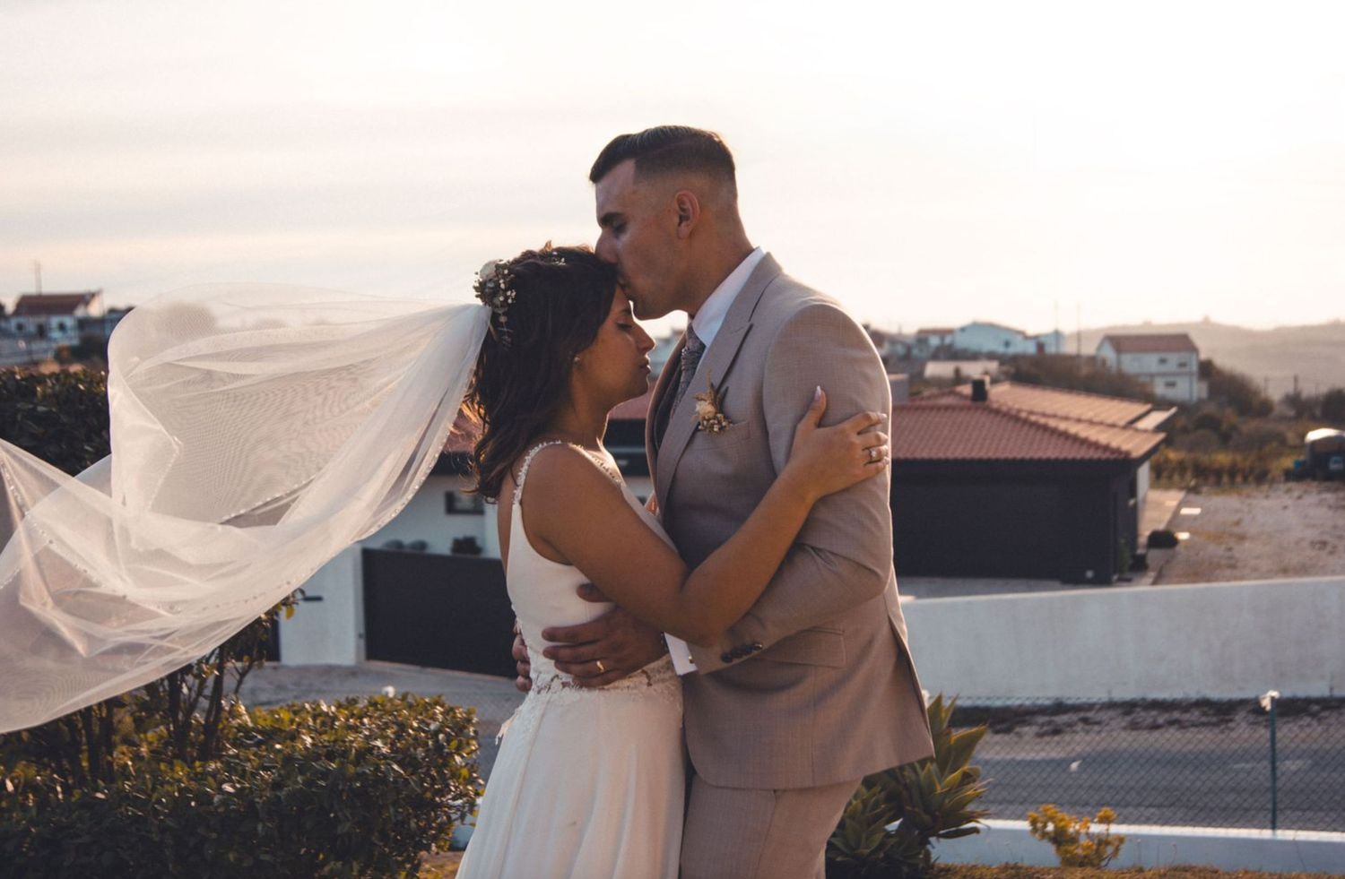 Wedding couple poses against desert landscape during golden hour sunset ceremony.