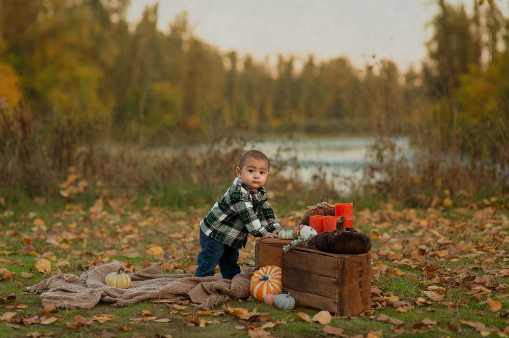 Children playing in fallen autumn leaves on a crisp fall day in a natural outdoor setting.