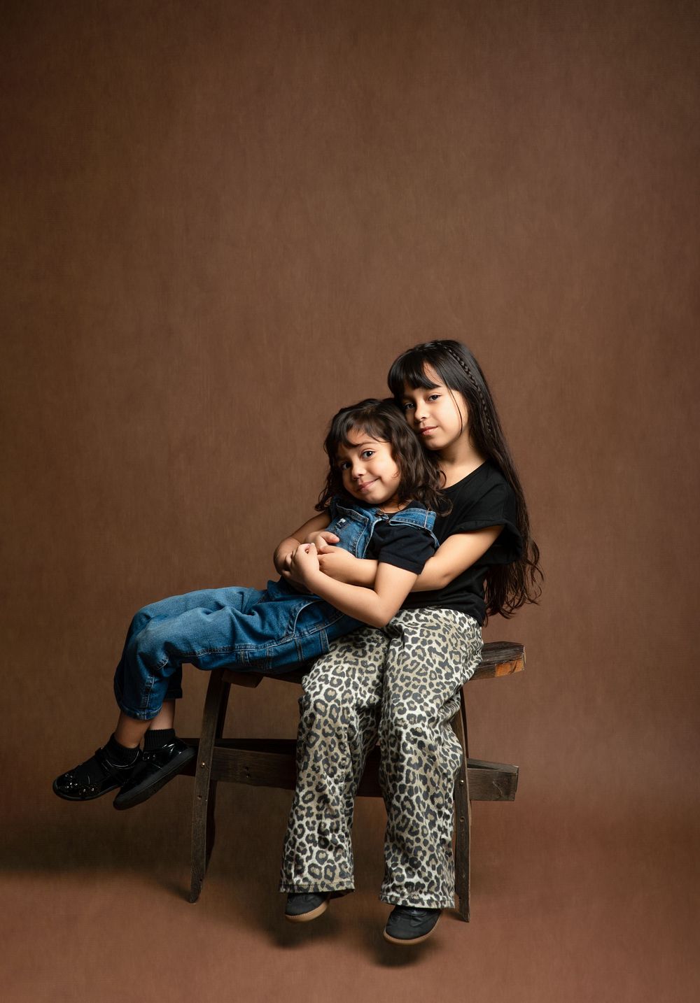 A series of studio portraits showing a tender moment between two people in casual clothing against a brown backdrop.
