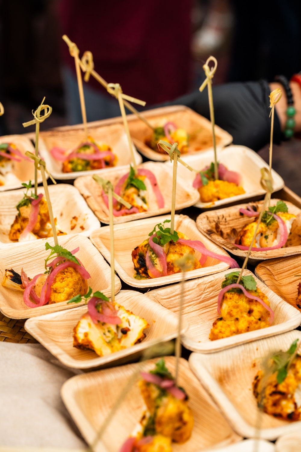 Elegant appetizers served in wooden boats with decorative garnishes at catering event.