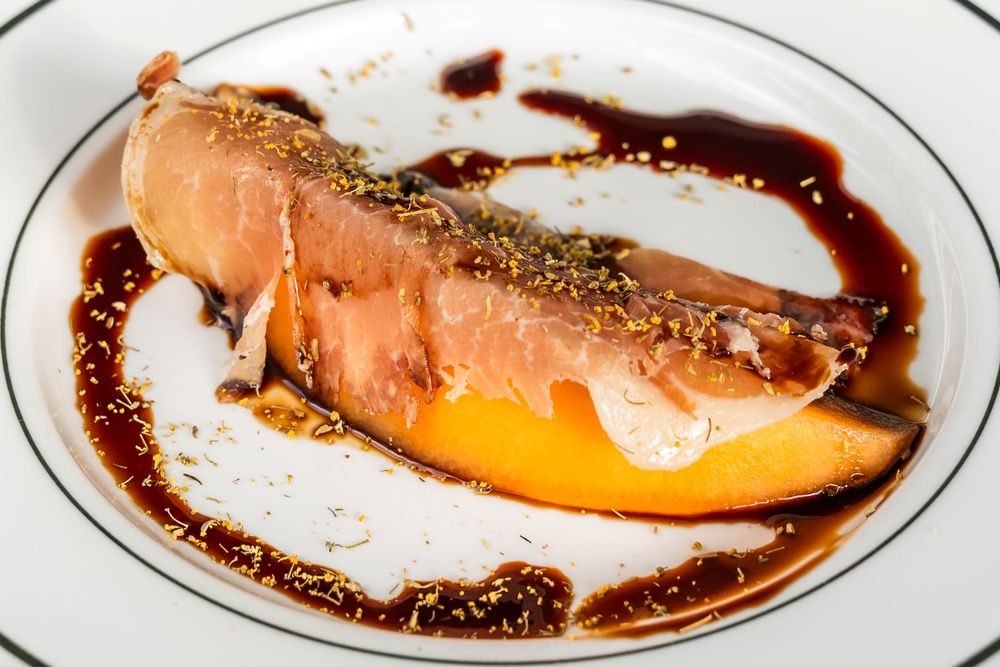 A series of white plates with sliced salmon and citrus garnish arranged in a curved line against a dark background.