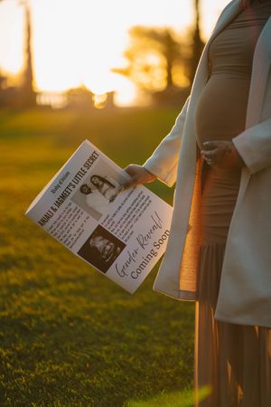Hands holding tickets or papers at sunset with golden sunlight illuminating the green grass in the background.