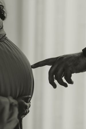 Black and white close-up of two statues with fingers nearly touching, inspired by Michelangelo's Creation of Adam.