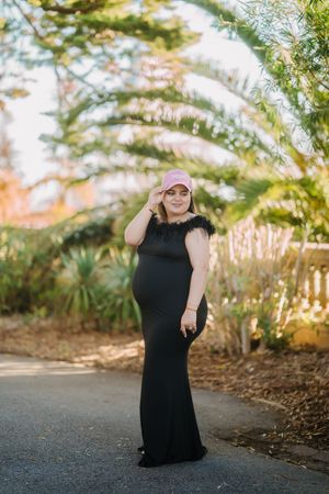 A person in a black dress poses playfully in a series of outdoor photos with trees and sunlight in the background.