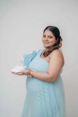A person in a light blue dress poses with a white cake against a white background in a photo series.