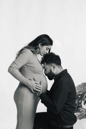 A romantic black and white maternity photo series shows tender moments between an expectant couple.