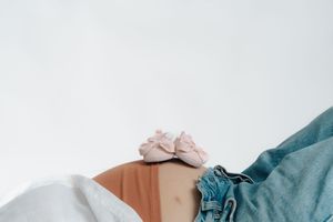 A person lies on rumpled blue bedding and white sheets with their face turned away from the camera.
