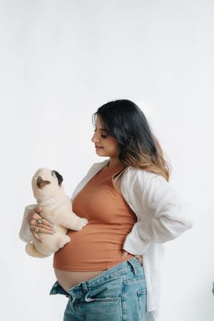 Three progressive views of a woman in blue jeans and coral top playing with a white teddy bear against white background.