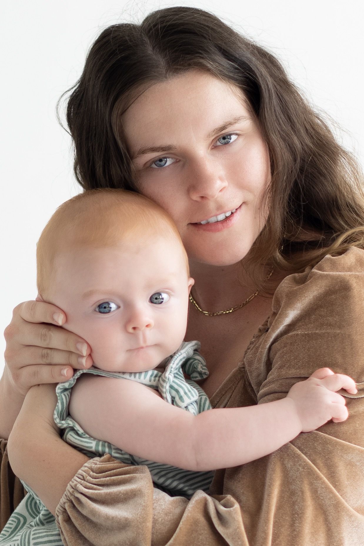 A tender moment between parent and baby as they embrace in a warm, intimate portrait.
