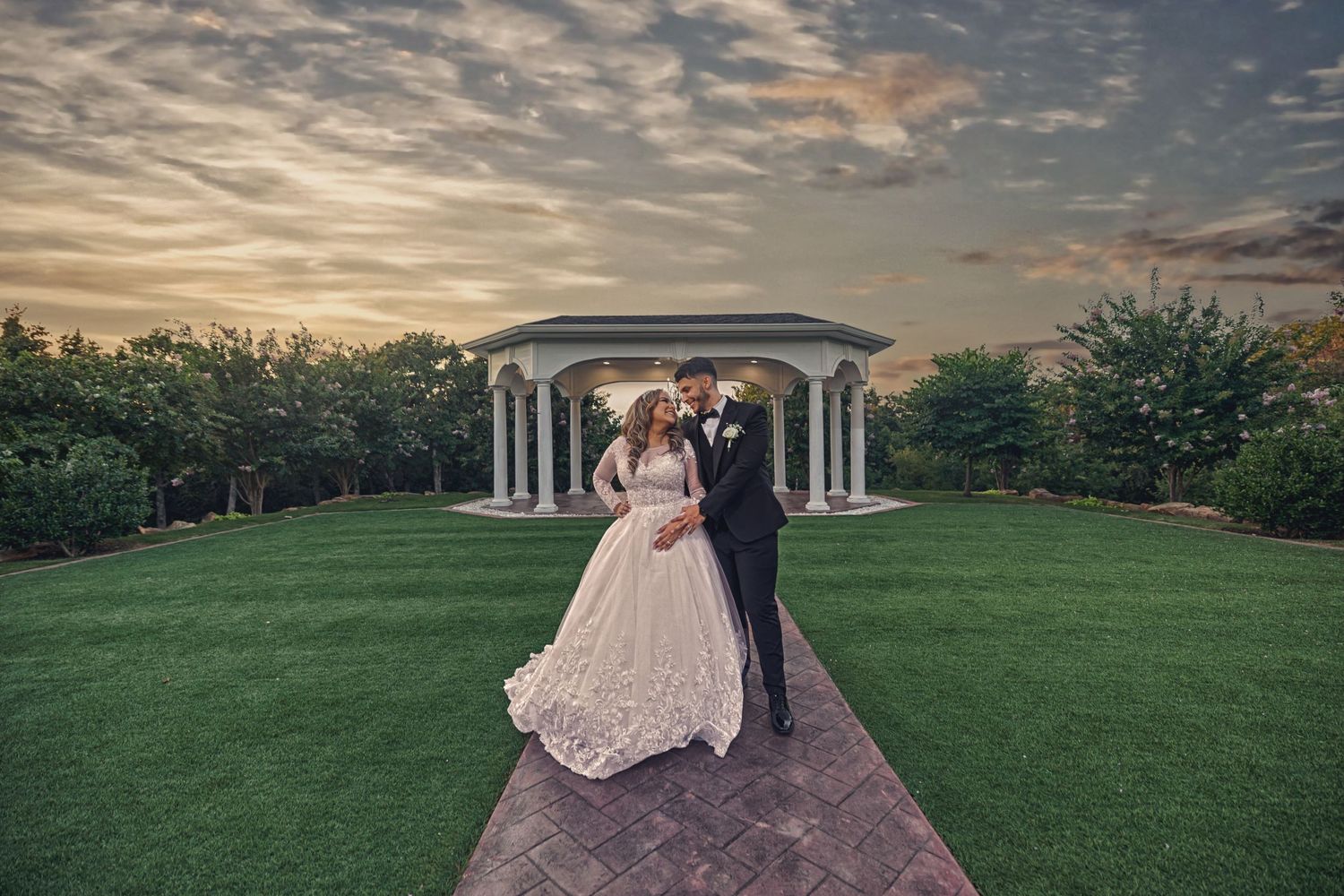 Romantic wedding photography at The Springs in Weatherford, TX featuring a bride in a lace ballgown and groom in a black tuxedo