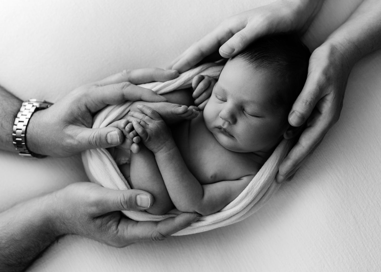 Sleeping newborn baby resting peacefully against white textured background in natural light.