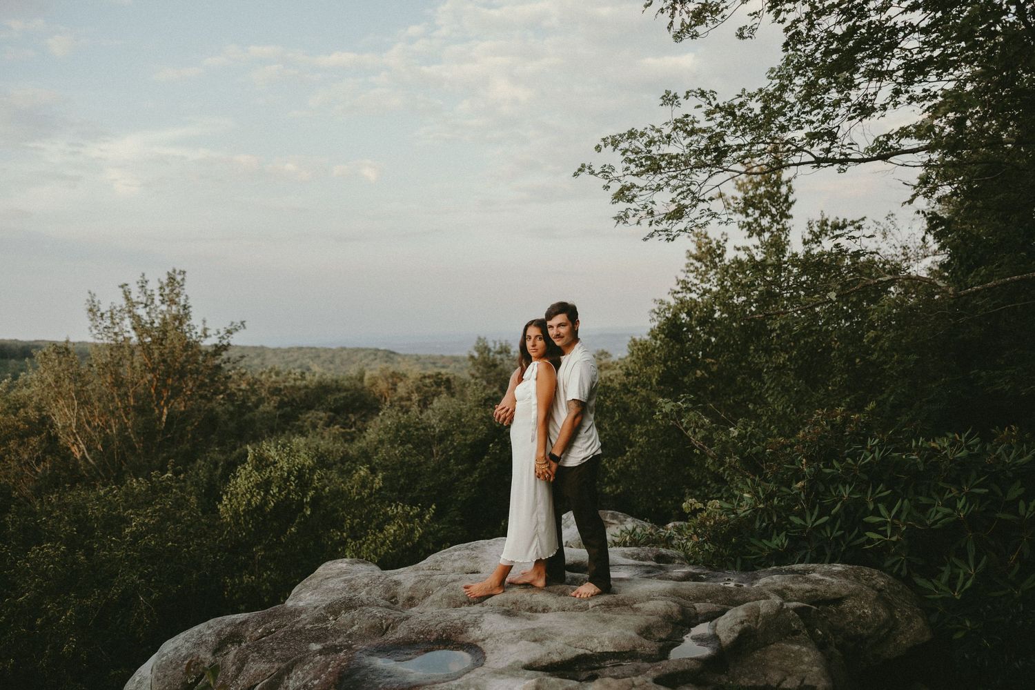 Golden hour portrait session with couple standing among autumn trees.