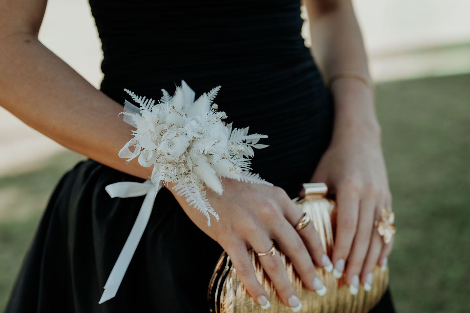 Close-up detail shot of hands with formal accessories against a dark background.