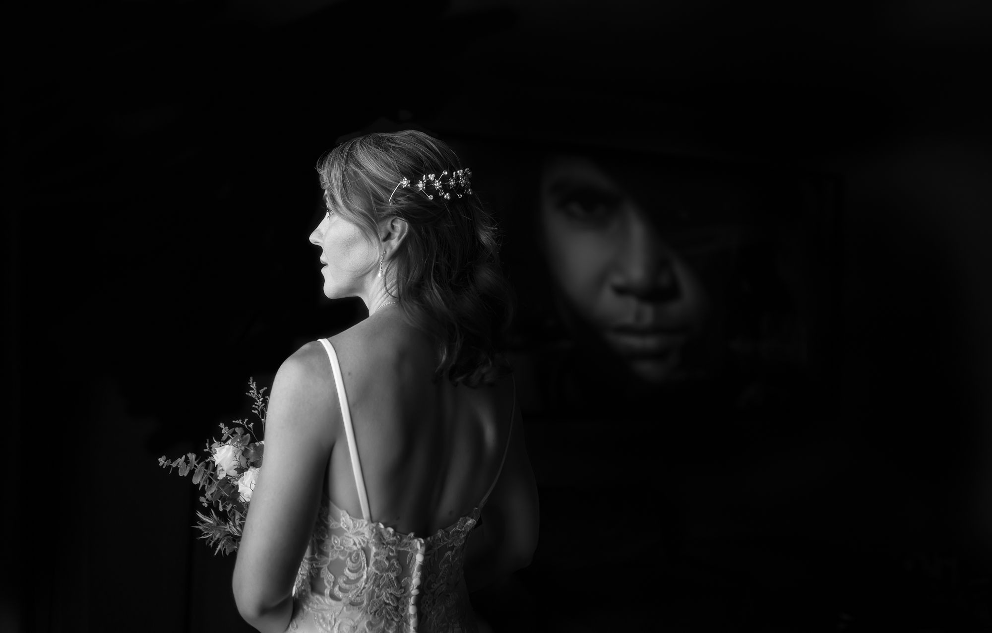 Dramatic black and white portrait showing a figure in a sparkly dress with a shadow reflection on dark background.