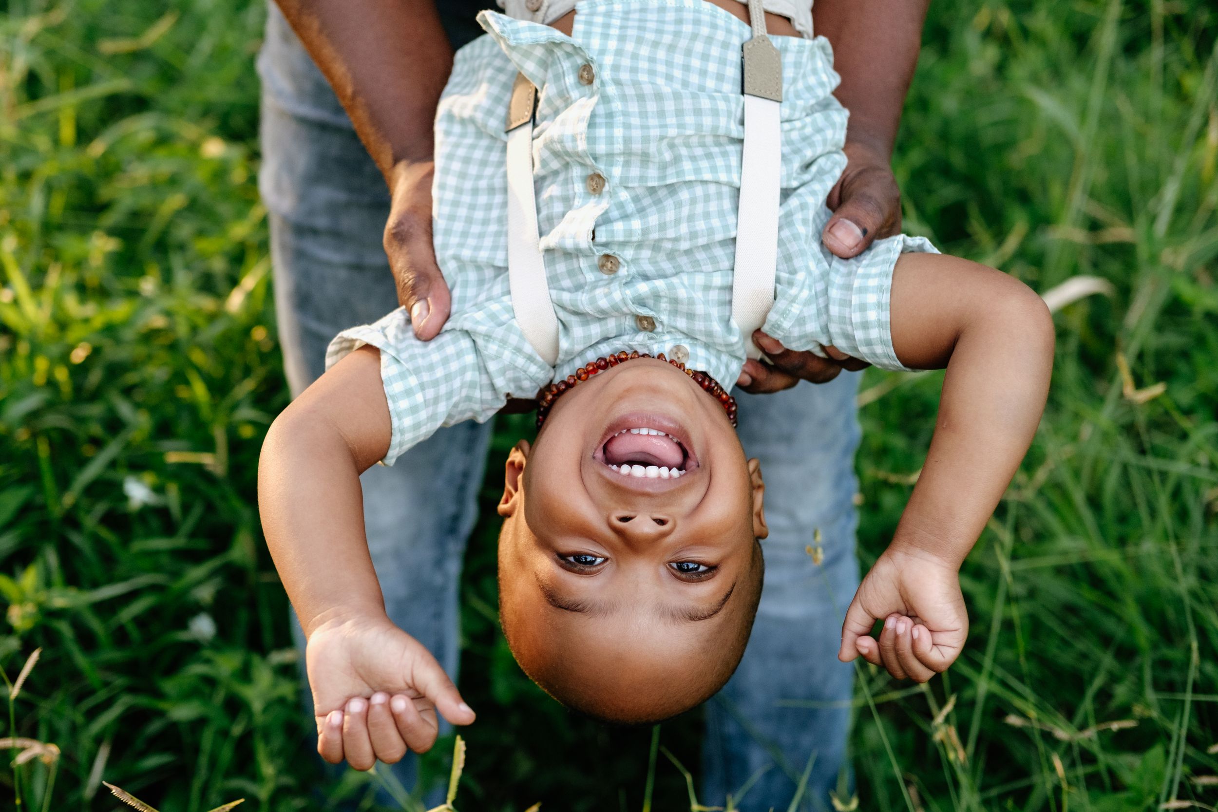 Little boy laughing as his dad holds him upside down