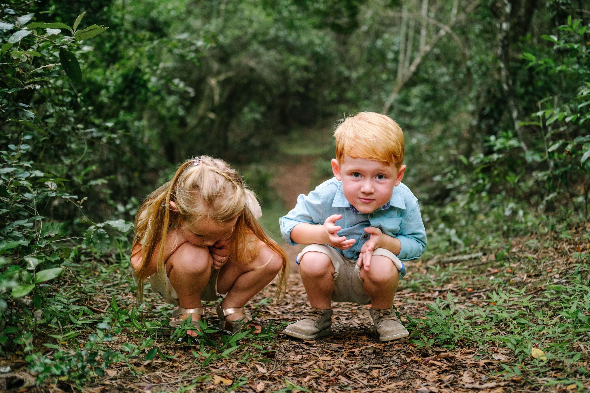 Two young children examining treasures on the forest floor