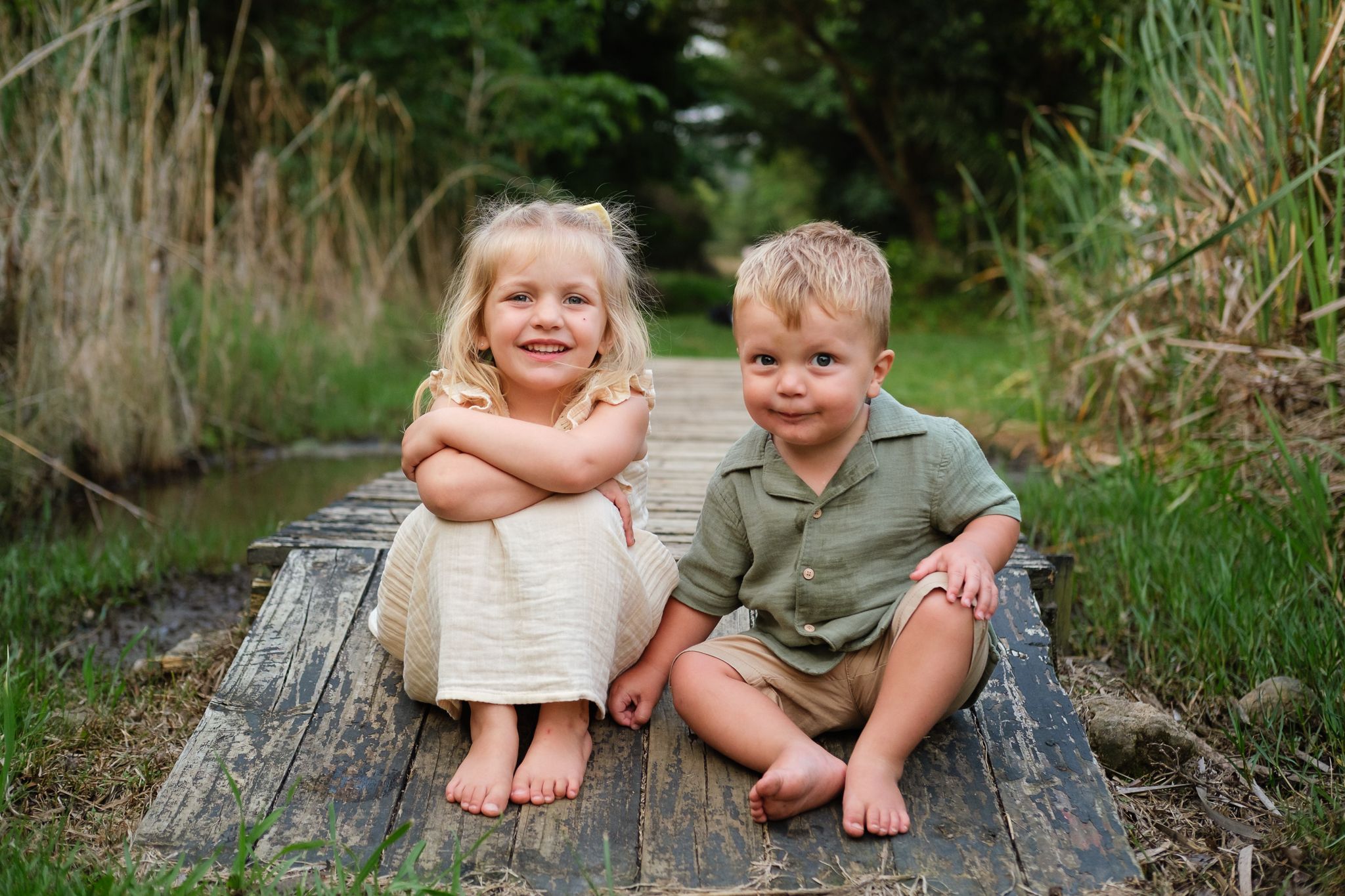 Brother and sister sitting together on a wooden deck, smiling