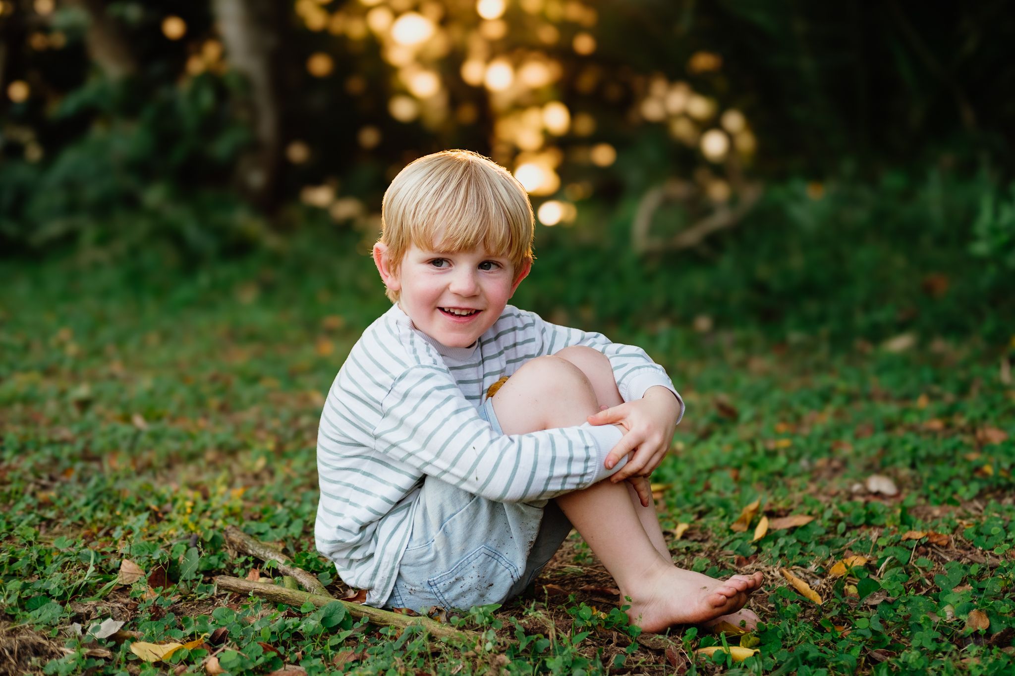 Little boy sitting on the grass laughing, full of curiosity and wonder