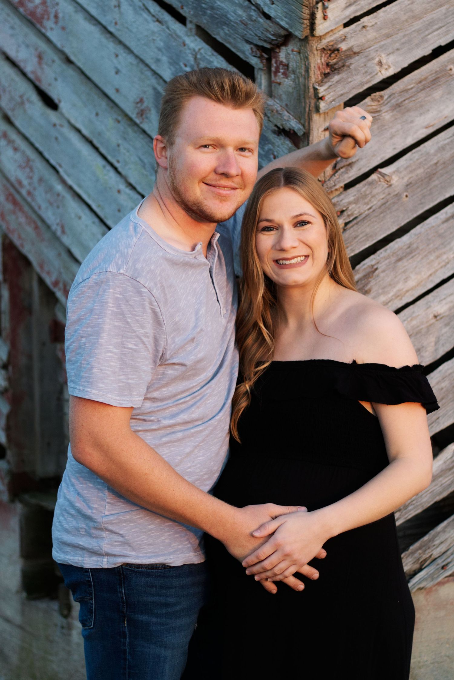 A couple posing in front of a barn