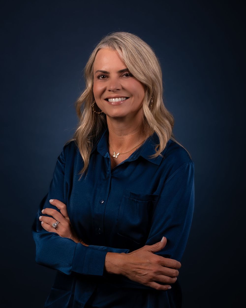 Professional headshots of a person in a navy blue blouse posing against a dark background.