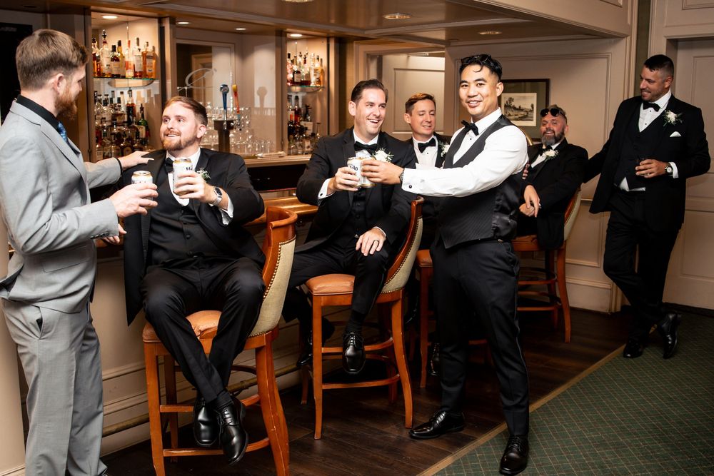 Wedding guests gathered in a cozy bar area with wooden furniture and warm lighting during a reception celebration.