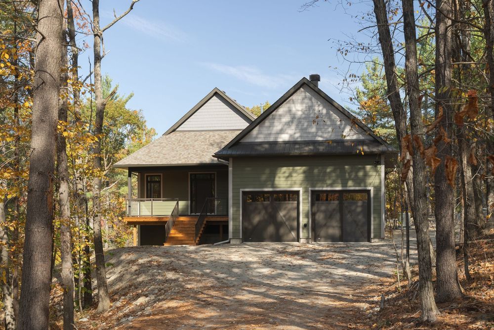A panoramic view of a rustic home nestled among autumn trees in a tranquil forest setting in Quebec