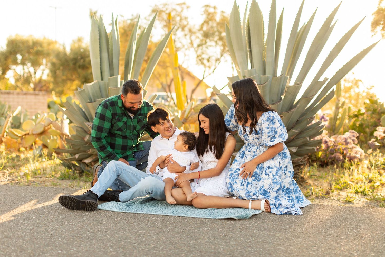 Family enjoying quality time together on picnic blanket near agave plants at sunset.