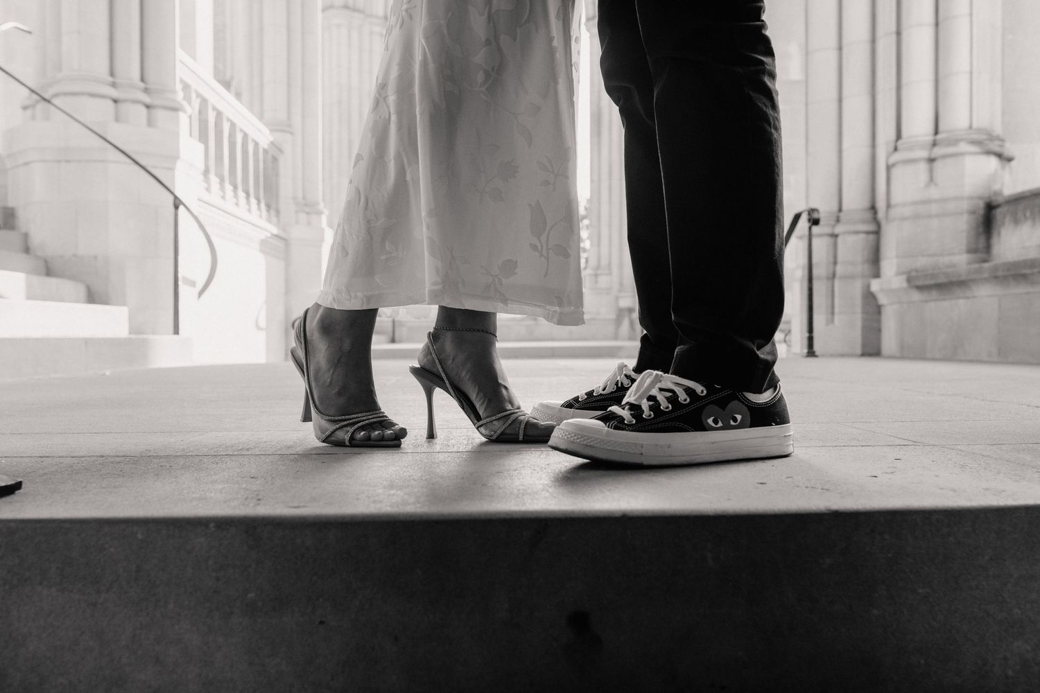 Black and white detail shots of formal shoes and dress hem on marble floor.