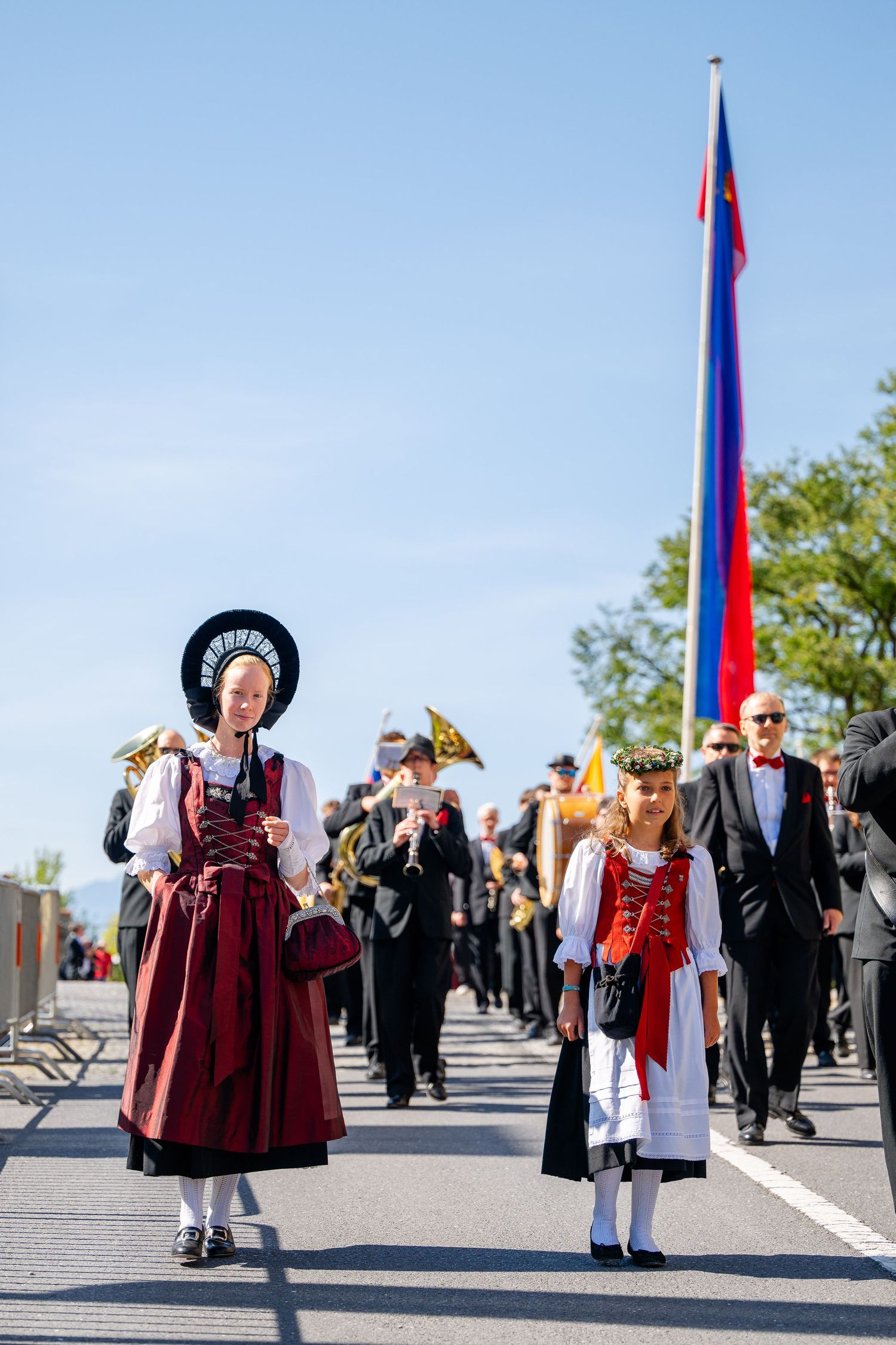 People in traditional Liechtenstein folk dress participate in a cultural procession with flags.
