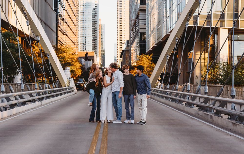 Family posing on suspended bridge in city embracing