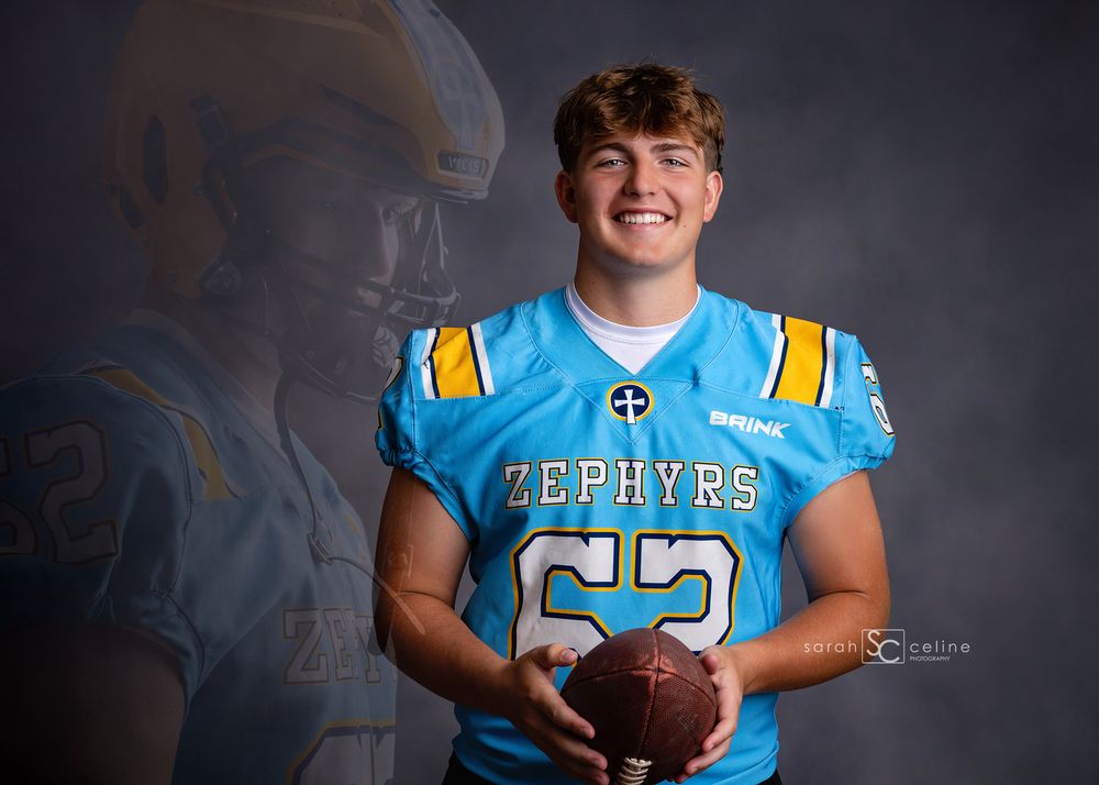 Young football player in Zephyrs teal jersey holding a football, posing for a professional team portrait photo.