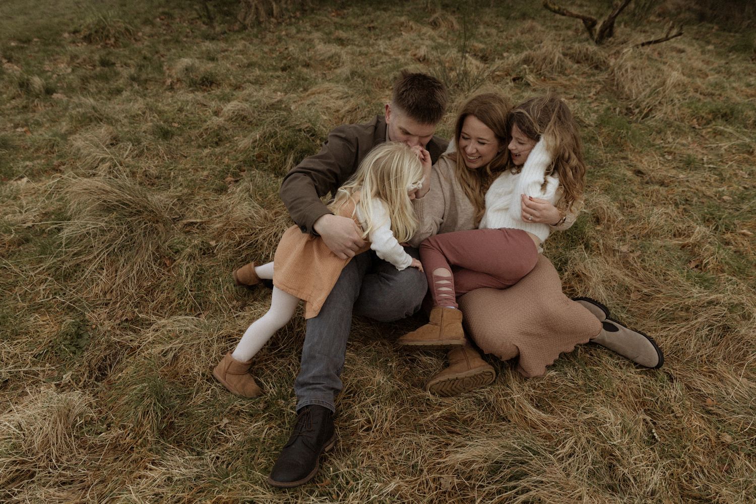 Parents lying on grass with their children gathered close, photographed from above