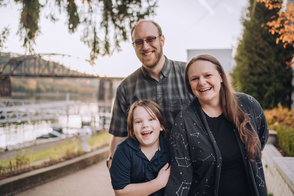 Family of three smiling with a bridge in the distant background. Shannon Konek, Pittsburgh Photographer