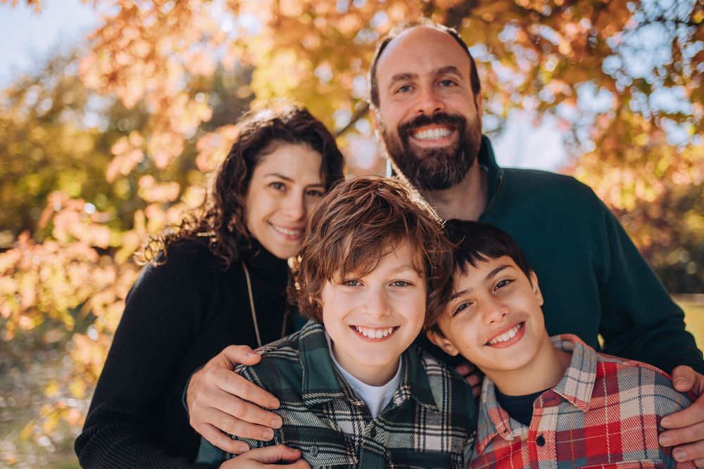 A family of four snuggles close against fall foliage. Shannon Konek, Pittsburgh Photographer